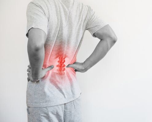 A man touched his lower back at the pain point because of the herniated intervertebral disc.